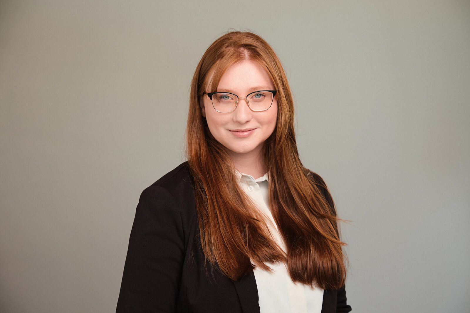 Simpson Thacher & Bartlett — Studioporträt mit Brille, grauer Hintergrund