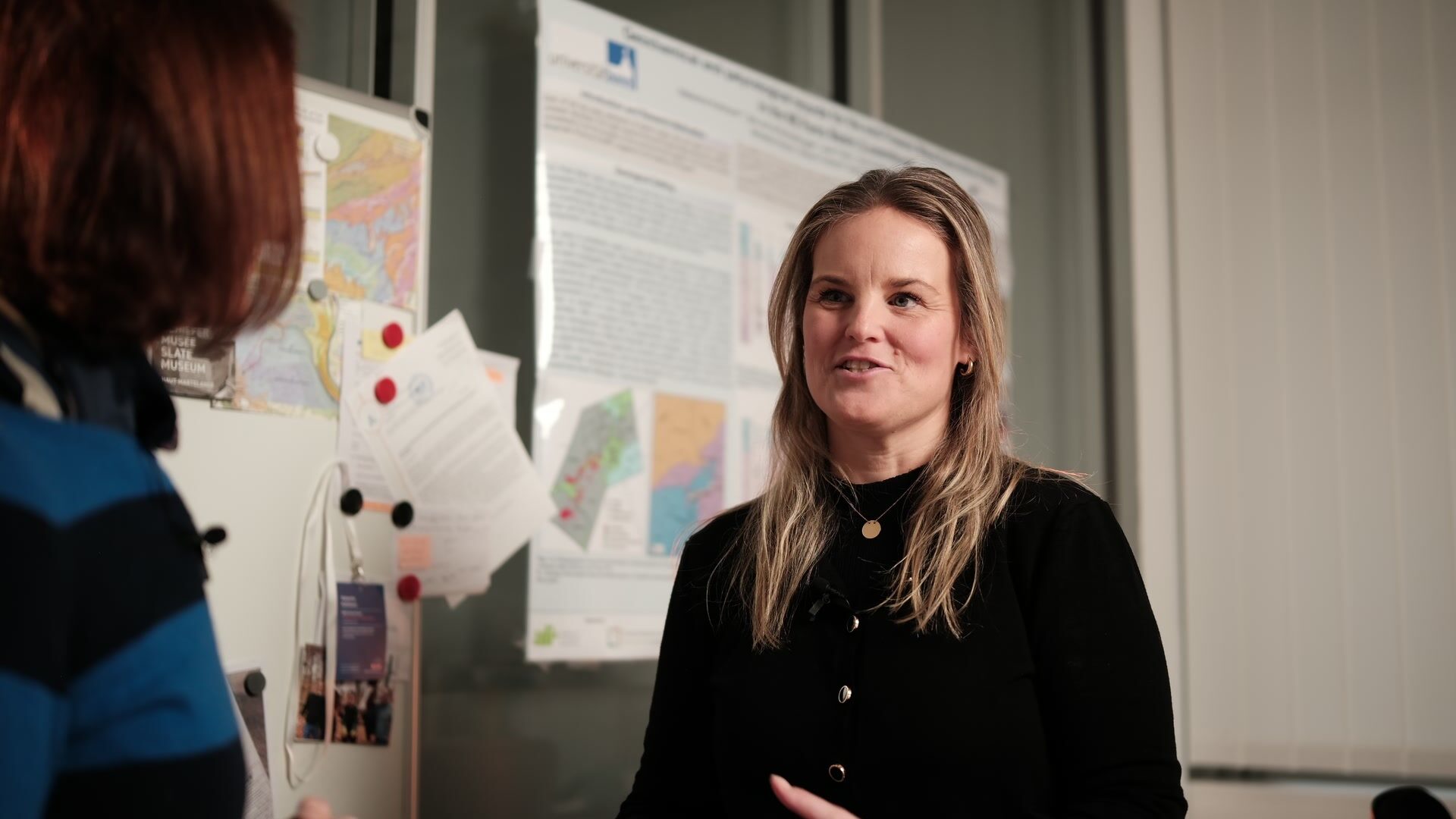 Universität Luxemburg — Standbild aus einem Interviewfilm: über die Schulter gefilmt, Plakatwand im Hintergrund