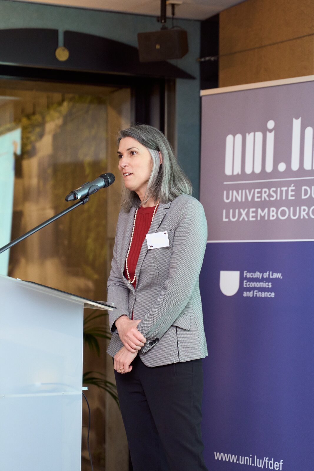 Universität Luxemburg — Rede am Rednerpult neben dem Banner der Universität